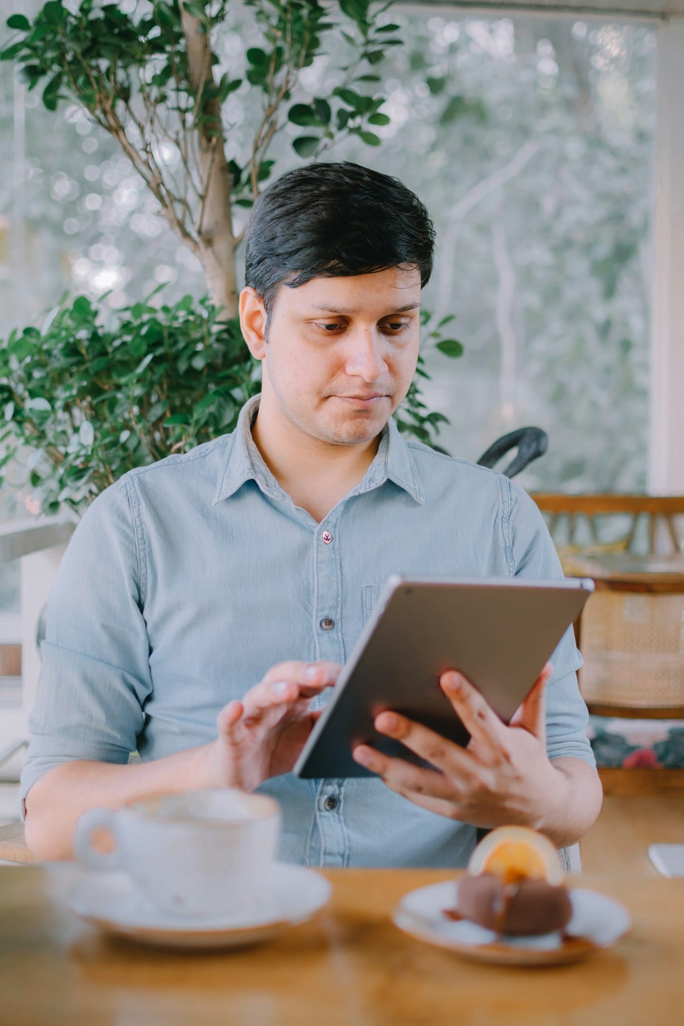 A man reading a tablet at a café table