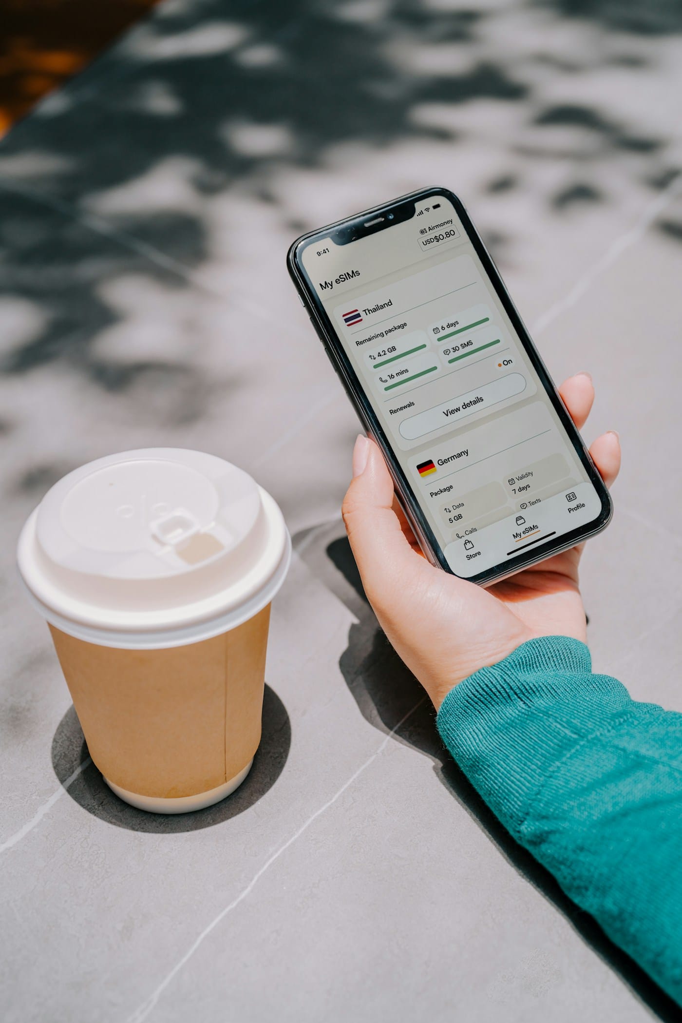 A phone in hand next to a takeaway coffee